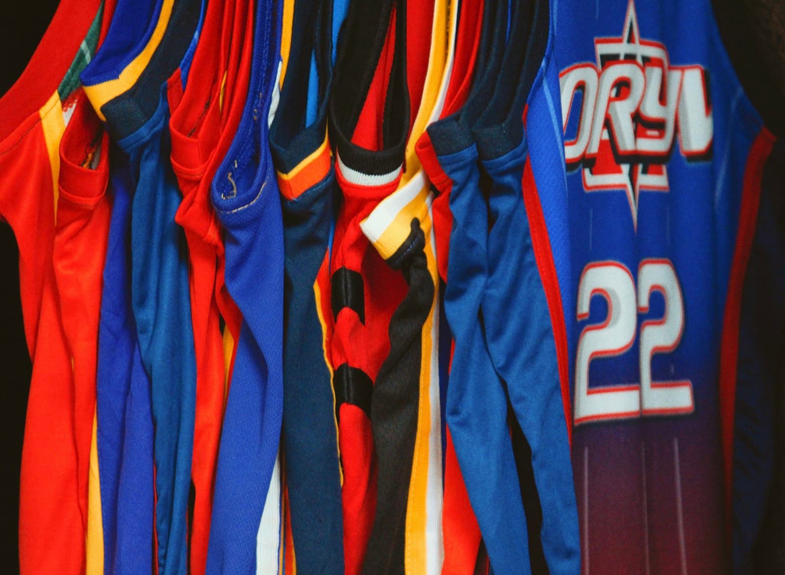 Rack of blue and red team sports jerseys ready for numbering