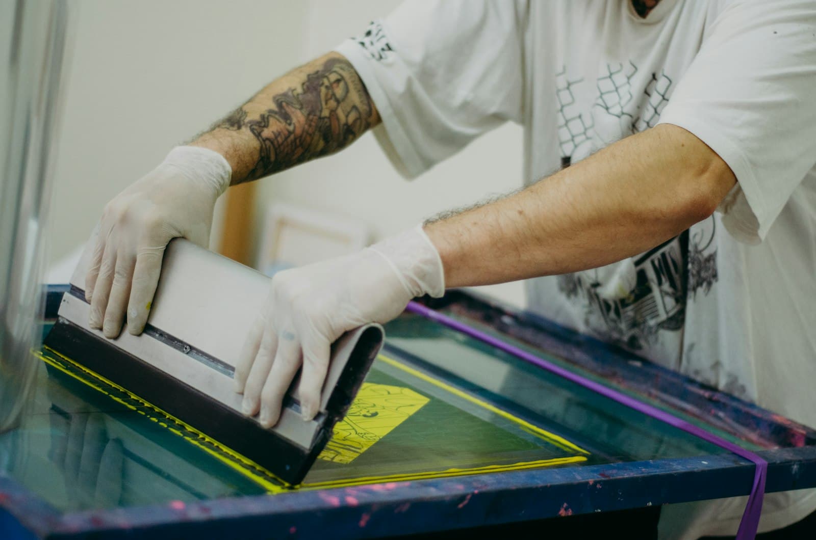 Print shop worker in gloves preparing a garment for direct-to-garment printing