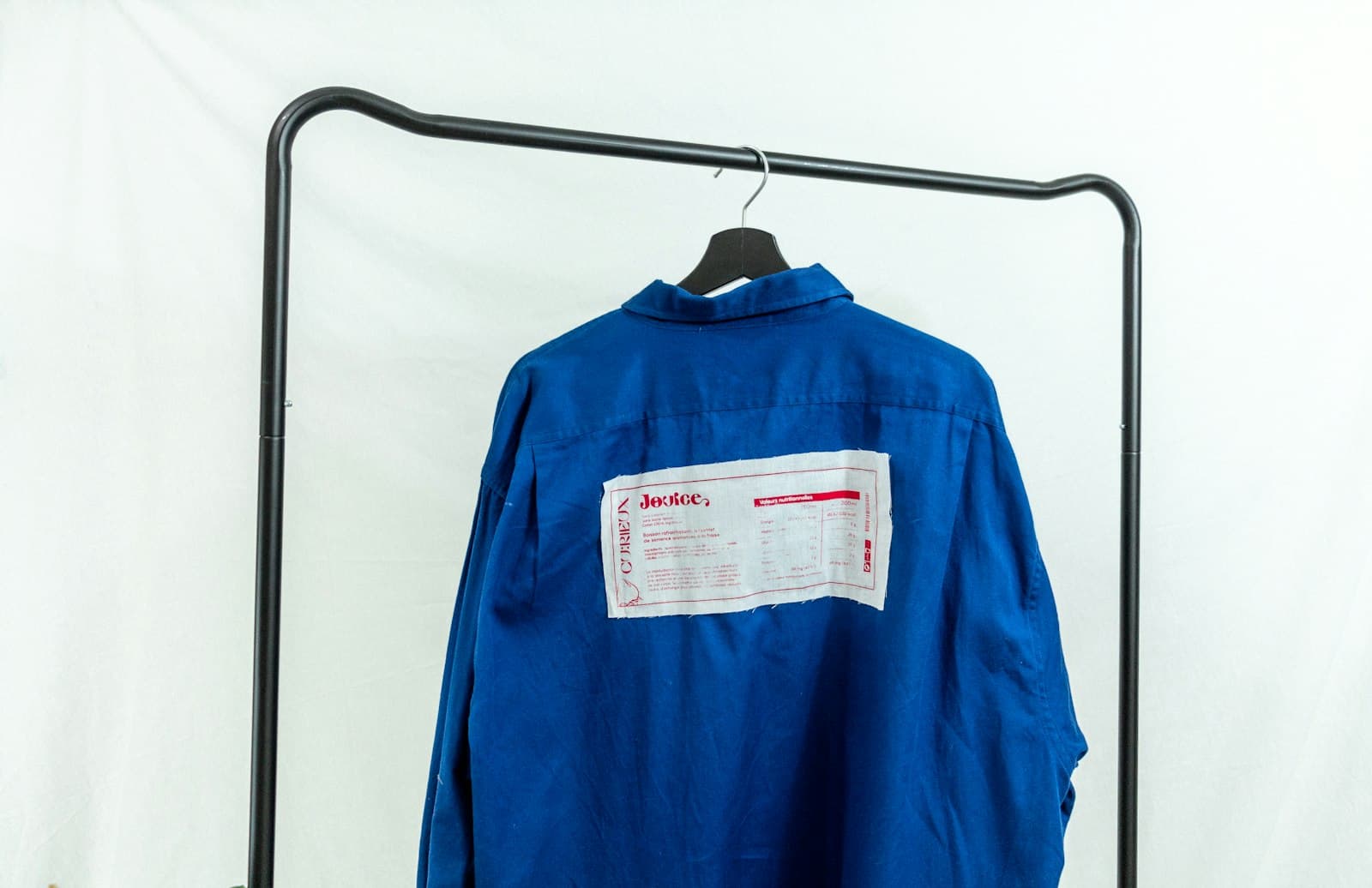 Blue embroidered work shirt on a hanger, part of a company uniform program