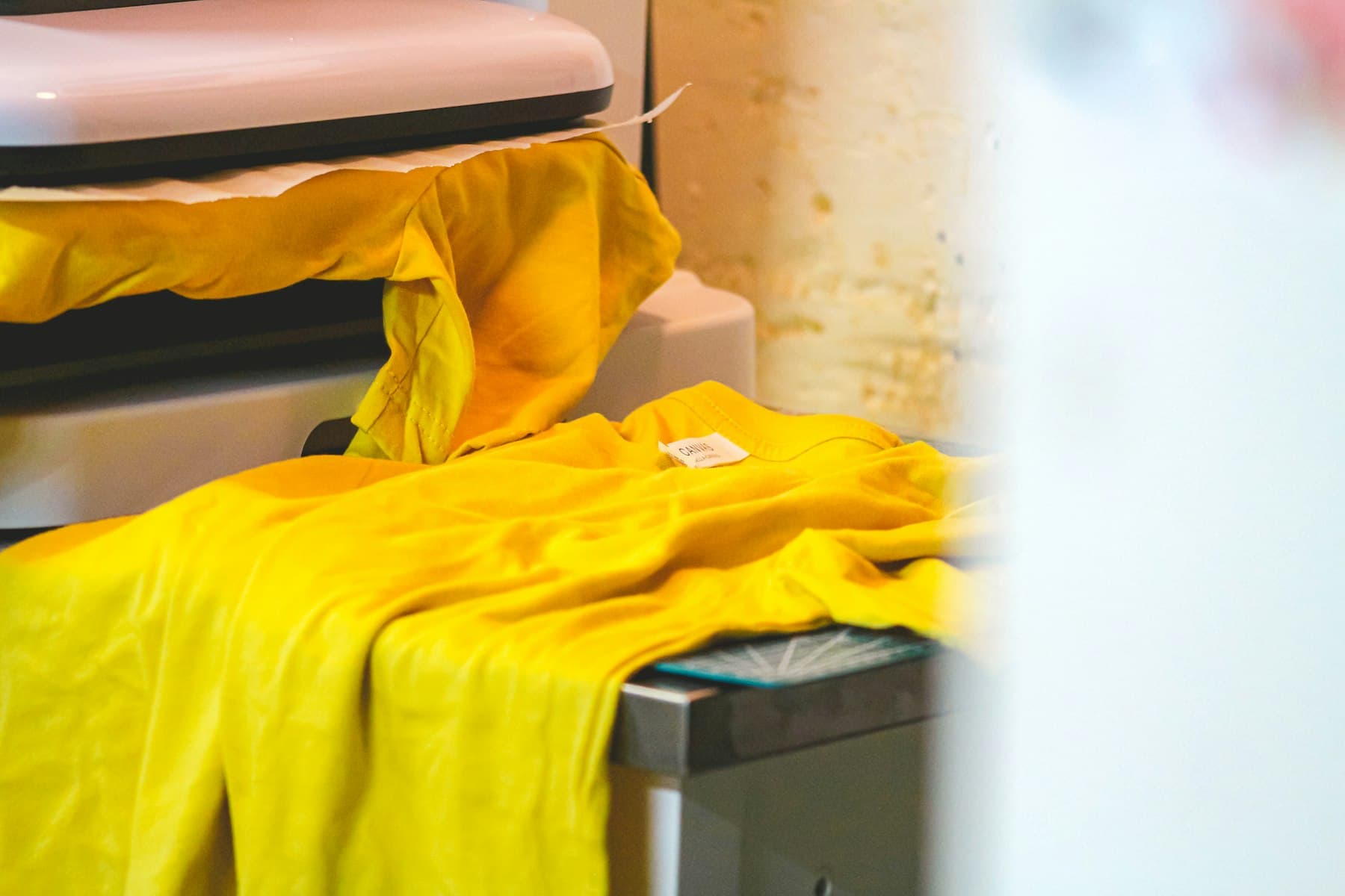 Yellow t-shirt being printed on a heat press machine